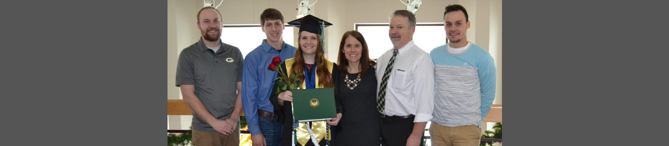 Katie Eichman posing with her family in her graduation cap and gown.