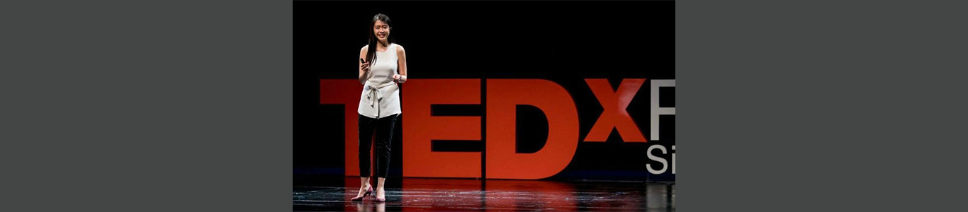 A photo of Maggie Lee onstage at a TEDx presentation in Singapore.