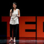 A photo of Maggie Lee presenting at a TEDx conference.