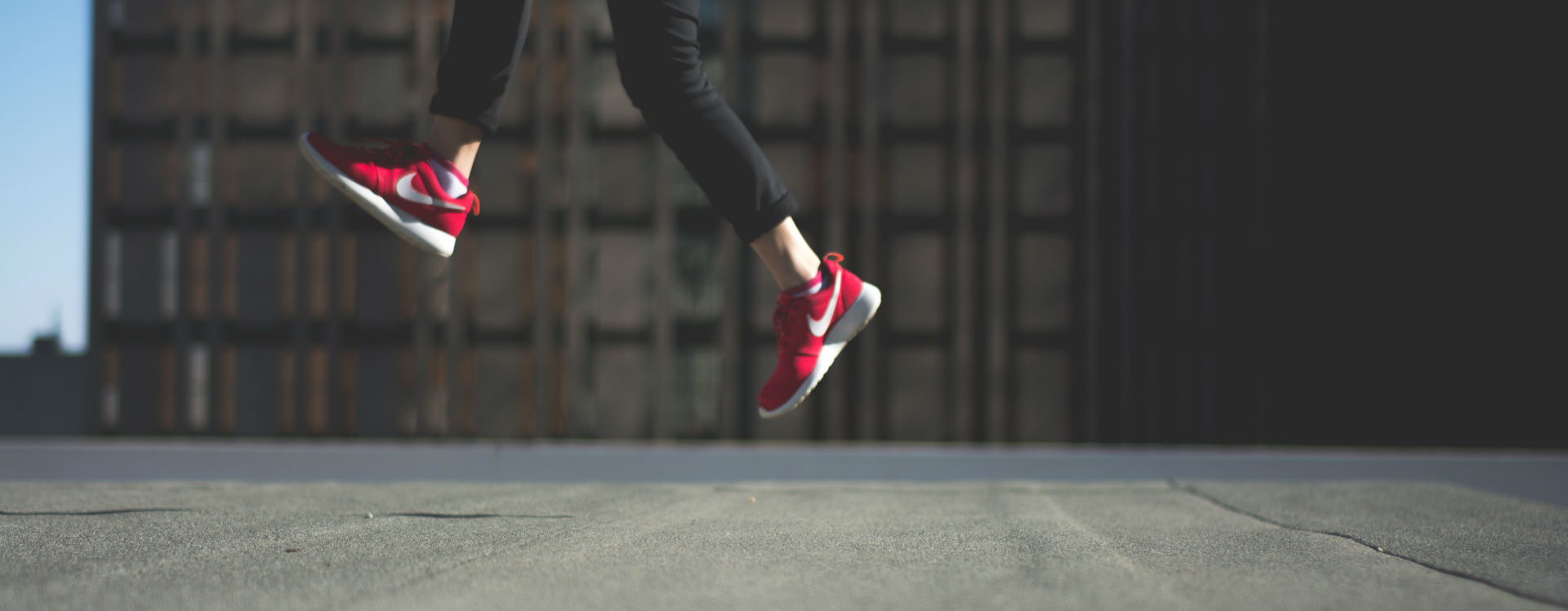 A person wearing bright red gym shoes jumping in the air.