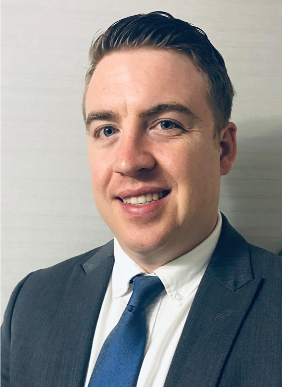 Professional headshot of Patrick Ritchie smiling in a suit.