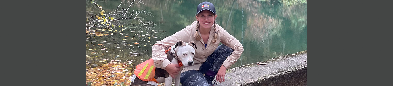 UW Sustainable Management master's student, Amy Kostelansky, posing with her dog Rio on a hike.