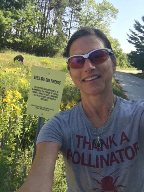 Beth Churchill posing next to a flower garden.