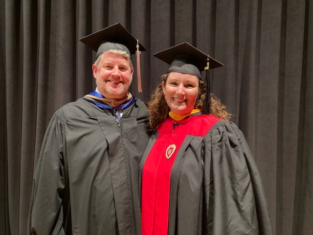 Shelley Nevins and her husband wearing their caps and gowns