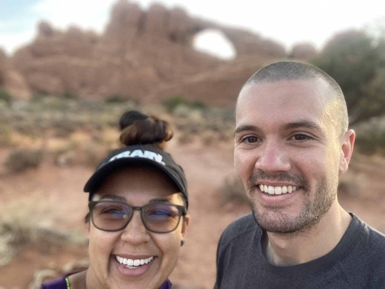 Chris and his wife Nathali taking a picture together outside while on a trip.