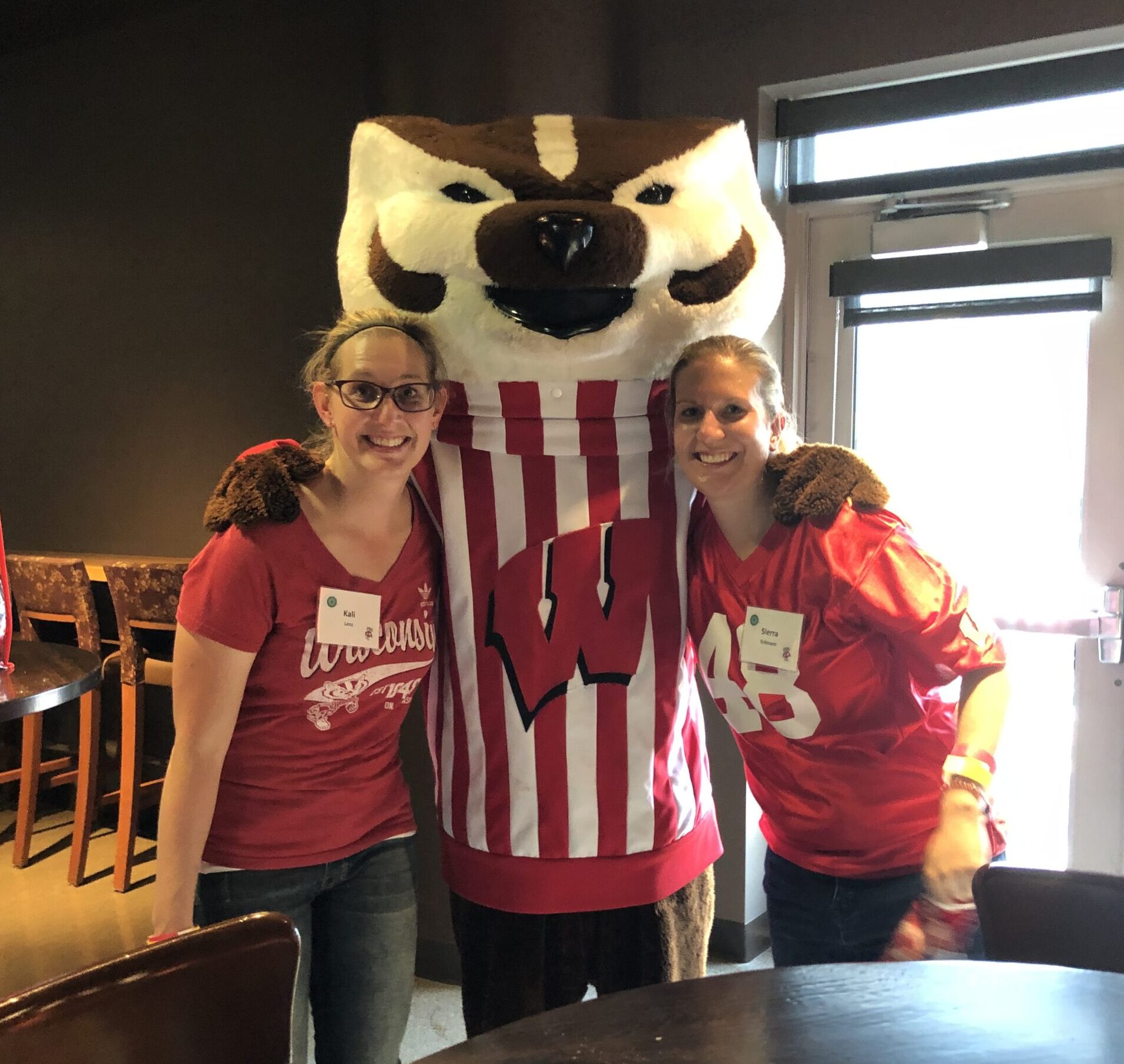 Sierra Erdmann standing with a friend and Bucky the Badger for a photo while wearing Wisconsin Badgers apparel. 