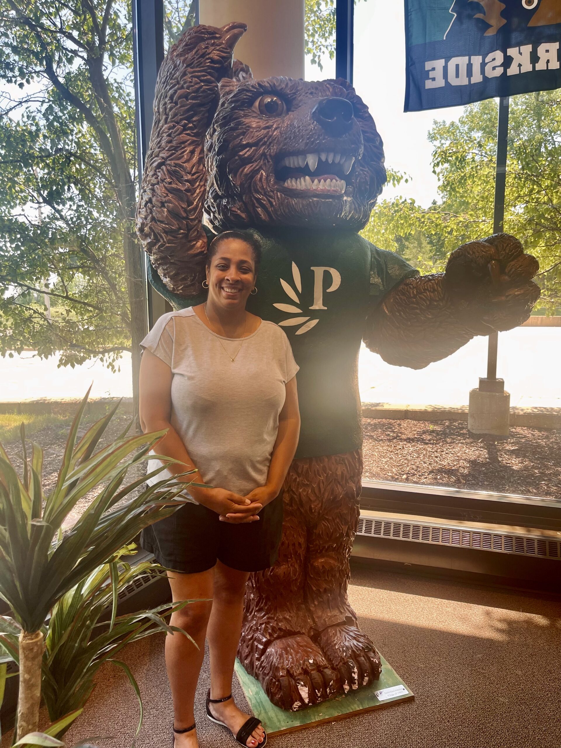 A photo of Rosetta Sellers-Varela at the UW-Parkside bookstore standing next to a statue of Ranger Bear, the school's mascot.