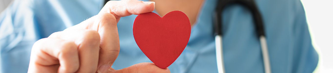 Image of a female healthcare worker holding a red paper heart. University of Wisconsin offers many programs for those interested in healthcare careers.