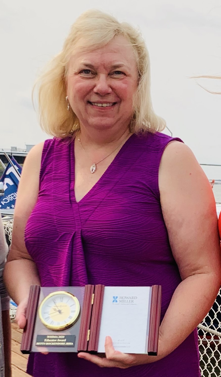 UW HIMT program director and capstone instructor Betty Rockendorf wearing a purple top and holding an award from the Wisconsin Health Information Management Association.