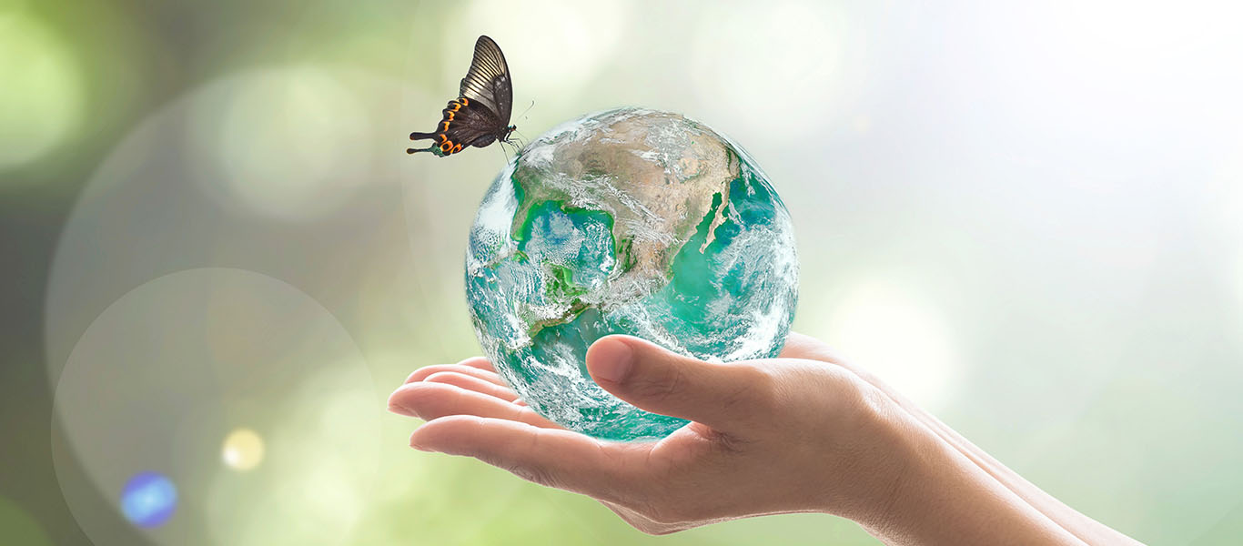 Hands holding a glass globe of the earth with a butterfly perched on top