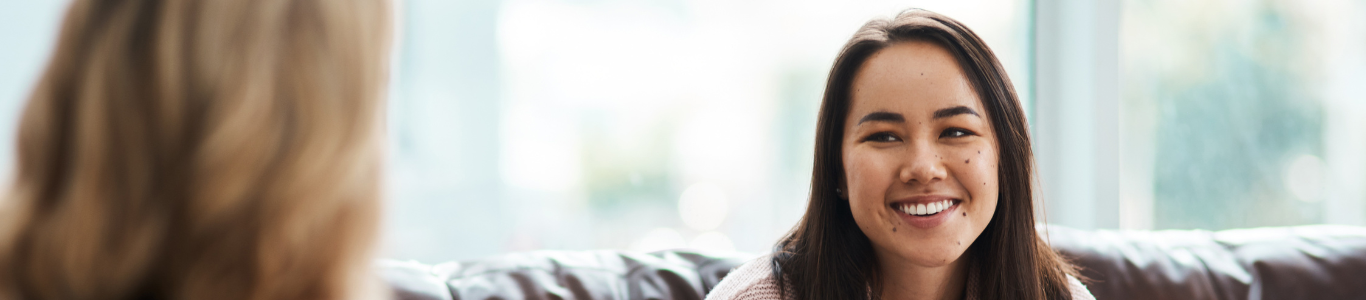 A look at mental health counseling as two women have a conversation on a sofa.