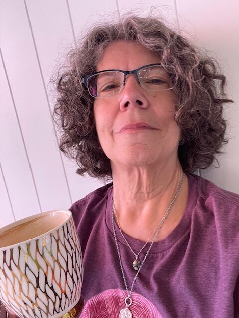 Jodi grinning while holding a coffee mug