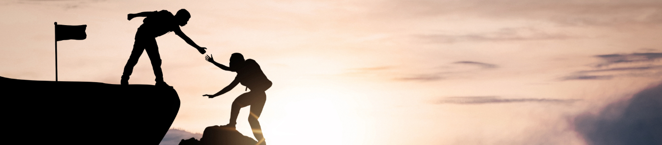 person helping another person climb up a rock, illustrating leadership