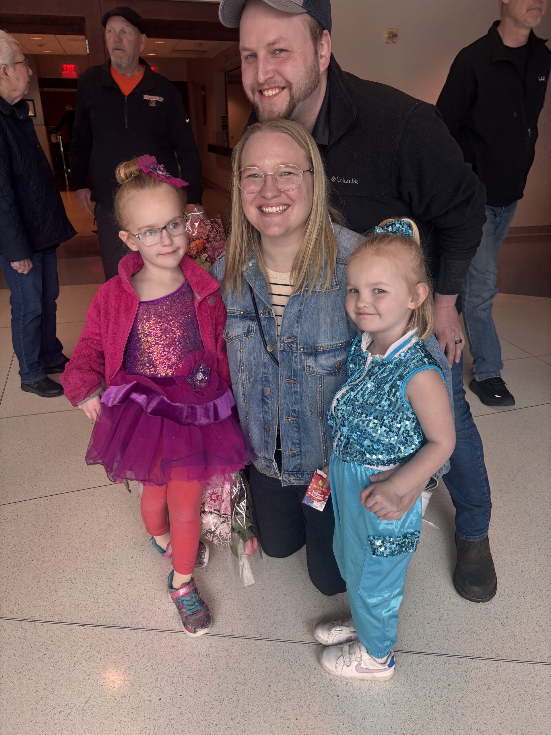 Brooke takes a picture with her family as her two daughters are dressed up for a dance recital. 