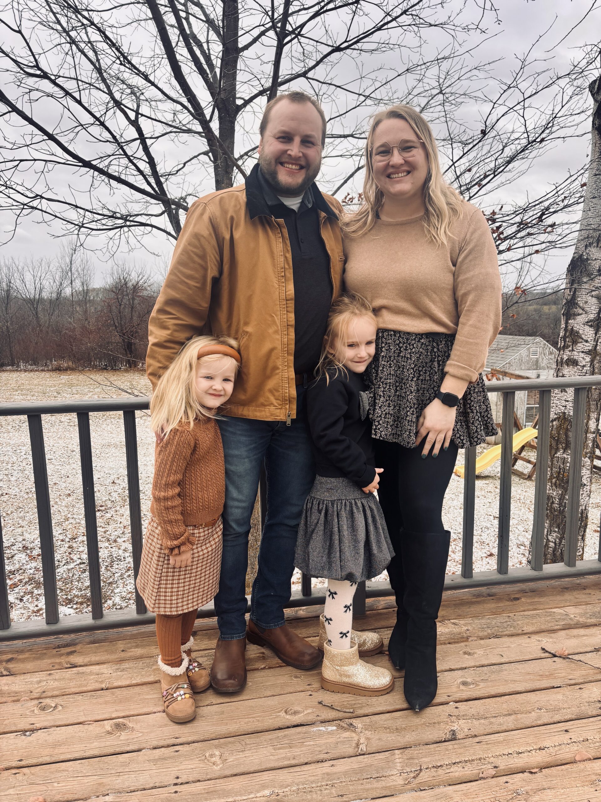 UW Digital Marketing student Brooke Hanson stands with her husband and two daughters on a deck outside. 