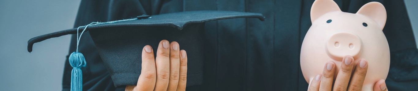 person holding a graduation cap and a piggy bank